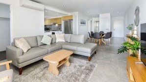 Una sala moderna con un sofá seccional gris, una mesa de centro de madera y un comedor con mesa y sillas.