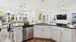 A modern kitchen with white cabinets, stainless steel appliances, and pendant lighting.