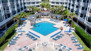 A hotel pool area with a central swimming pool, lounge chairs, and palm trees. - GulfScape2217 Seascape Condos 1bed1bath Beachfront Condo Ocean View from balcony (Galveston)