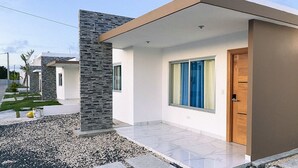Ein modernes Haus mit einer Stein-Fassade, einer Holztür und einer Pflasterterrasse.