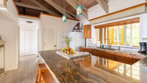 Una cocina moderna con una isla grande, armarios de madera e iluminación colgante.