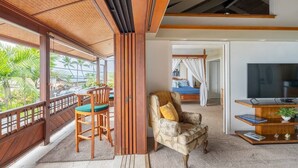 Una habitación con balcón, televisión, sofá y comedor con sillas.