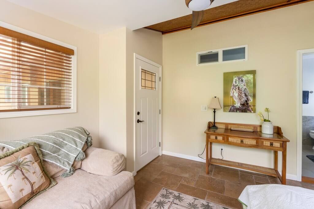 A cozy living room with a beige sofa, a wooden console table, and a door with a window above it.