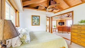 Un dormitorio con una cama, techo de madera, un cuadro, un aparador y un televisor.