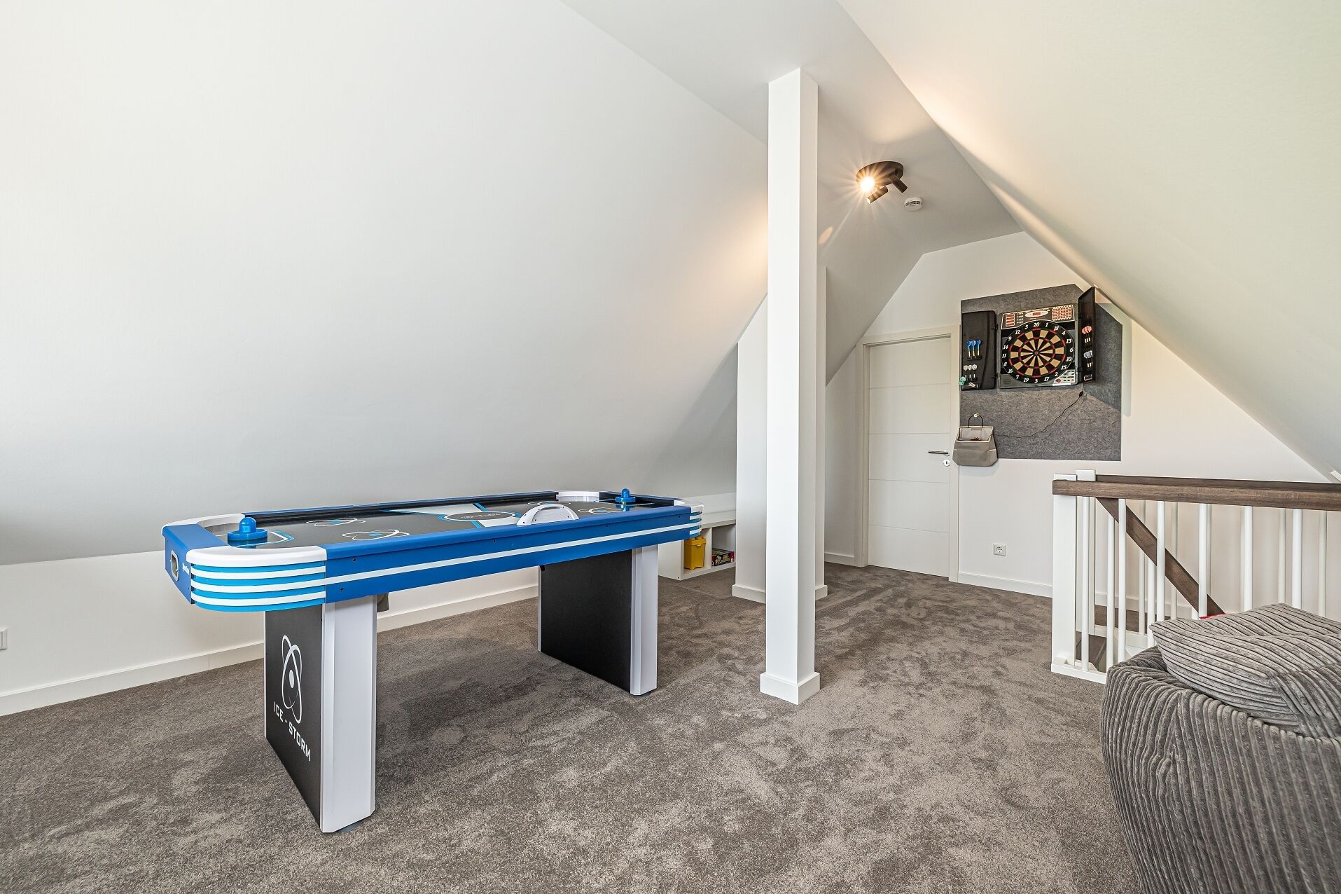 Une pièce équipée d’un baby-foot, d’un jeu de fléchettes et d’un coin salon confortable agrémenté d’un pouf à motifs.