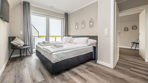 Une chambre moderne avec un grand lit, une chaise et une vue par la fenêtre.