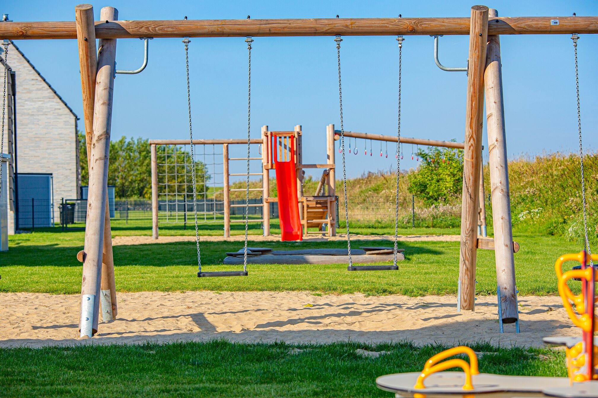 A playground with swings, a slide, and a climbing structure.