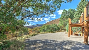 A paved road leading to a wooden structure with a staircase, surrounded by trees and hills.