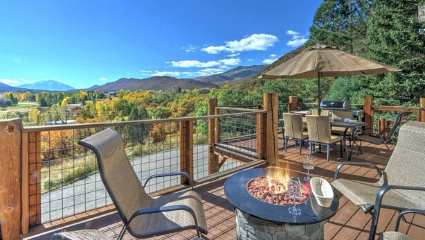 An outdoor patio with a fire pit, seating, and a view of mountains.
