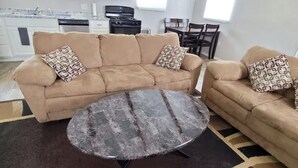 Ein Wohnzimmer mit einem beigen Sofa, einem runden Couchtisch und einem gemusterten Teppich.