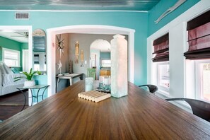 Enjoy meals in this dining area with a long table for four, a teal accent wall, and a large window.