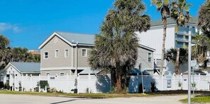 Stunning two-story building with a flat roof, surrounded by a white fence and palm trees.