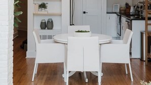 Une cuisine moderne avec des meubles blancs, une table de salle à manger ronde et un luminaire suspendu.