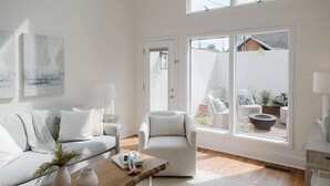 Un salon moderne avec un canapé, un fauteuil et une table basse, de grandes fenêtres donnant sur le jardin.