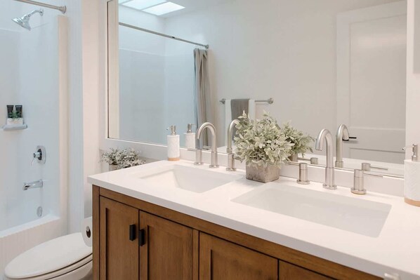 A modern bathroom with a double sink, a large mirror, and a shower area. - 29 South by Mira-Mar (Wilmington)