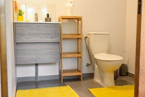 Bathroom features a grey cabinet, shelf, and wooden stool.