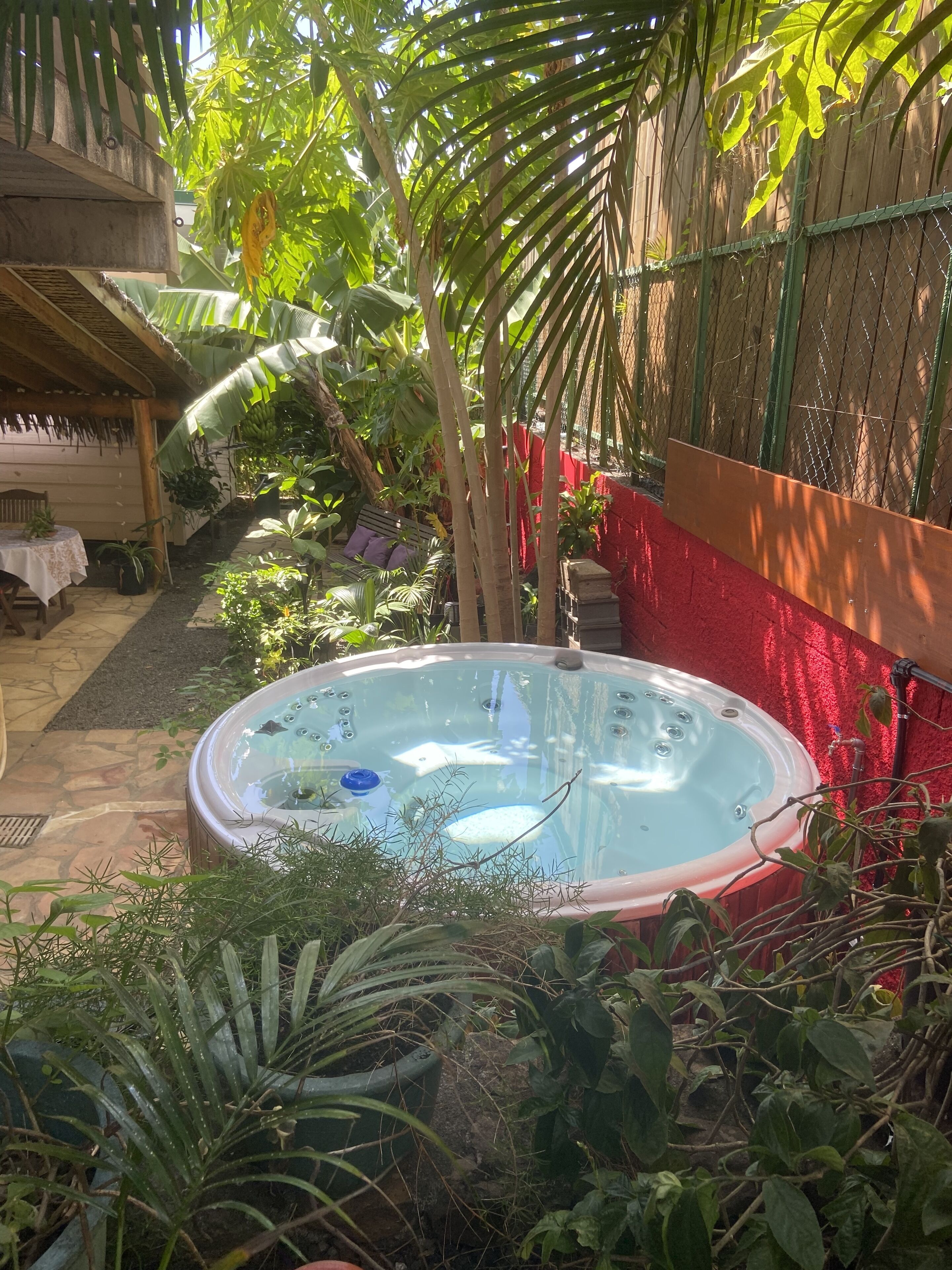 A hot tub surrounded by lush greenery and a wooden deck.