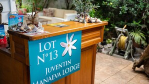 A wooden reception desk with a sign reading "LOT N°13 JUVENTIN MANAEVA LODGE".
