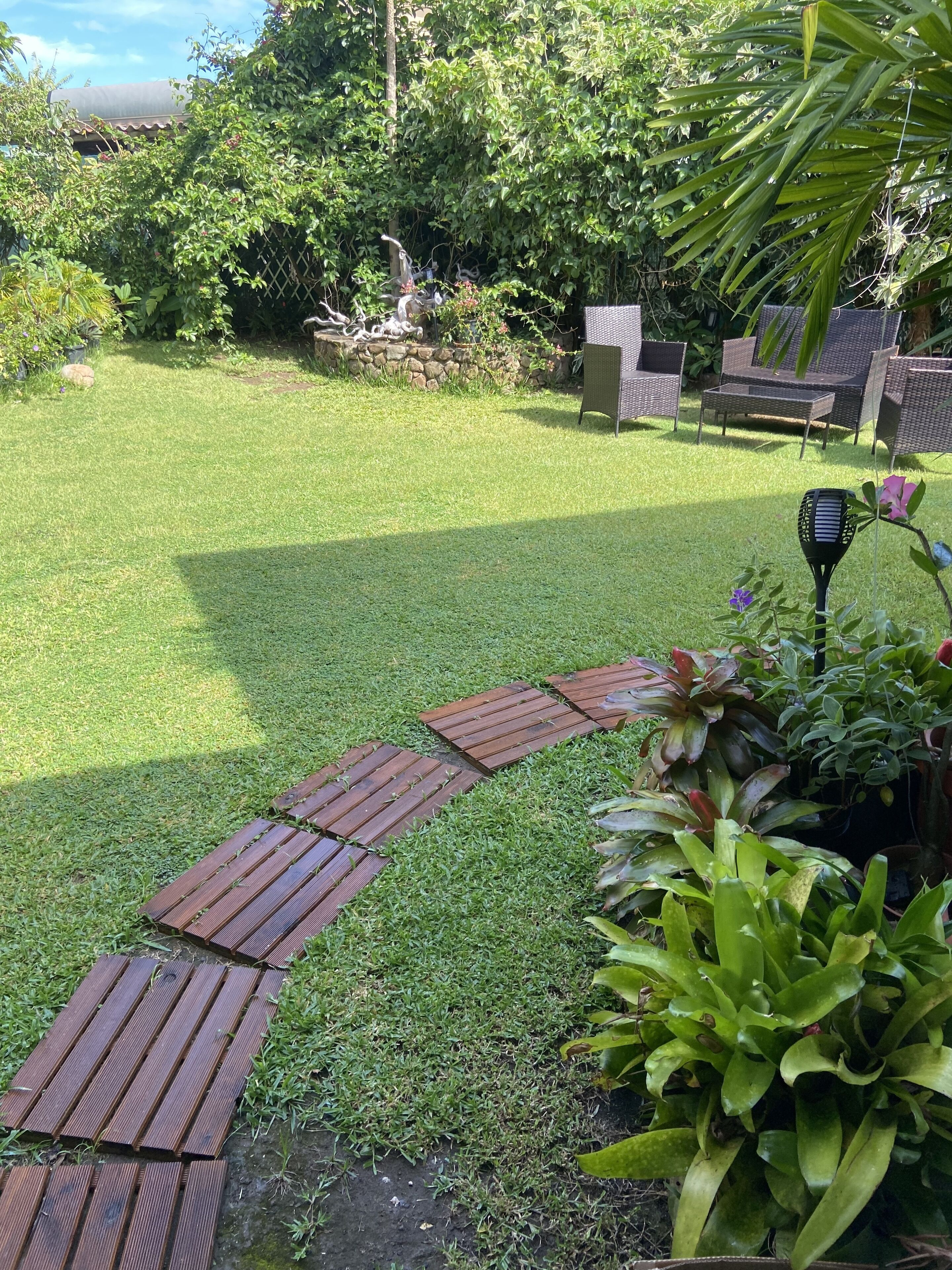 A well-maintained lawn with a wooden pathway leading to outdoor furniture.
