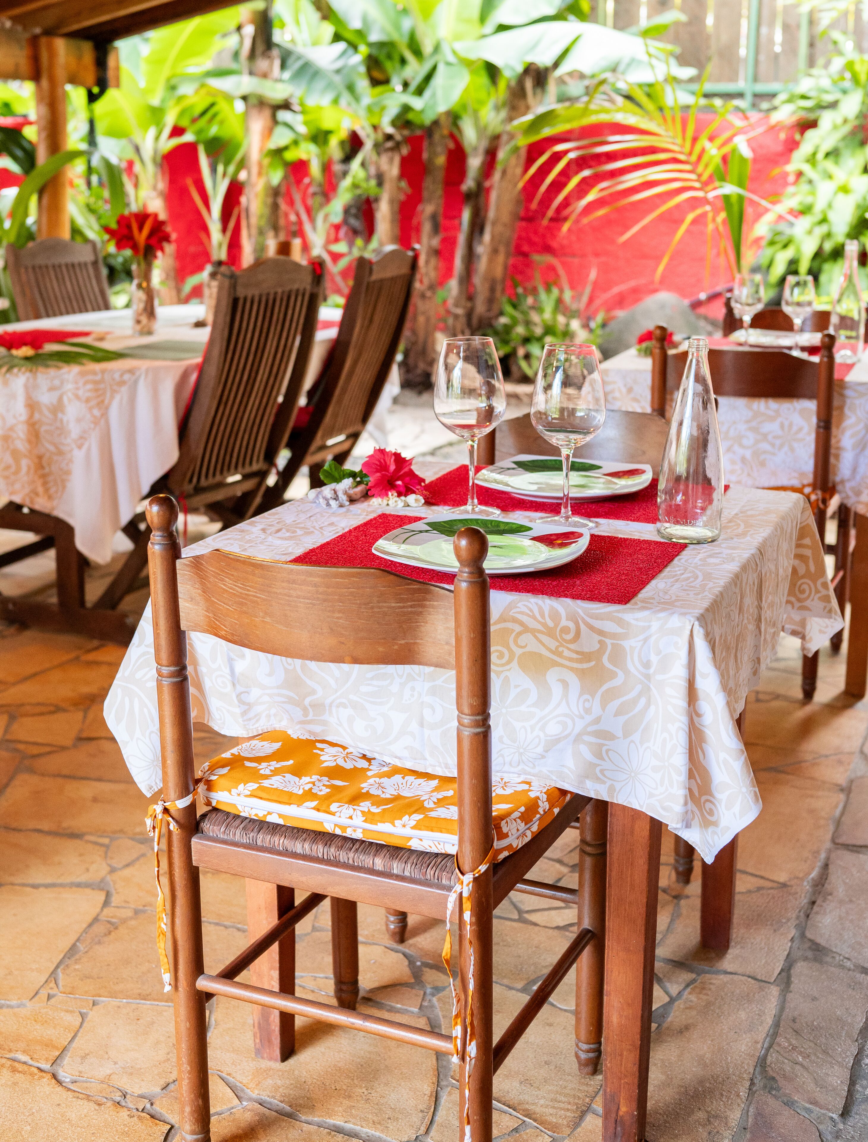 Un restaurant avec des chaises et des tables en bois, dont certaines sont agrémentées de sets de table rouges.