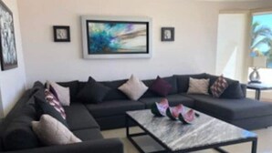 Een moderne woonkamer met een modulaire bank, een salontafel en abstracte kunst aan de muur.