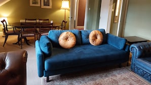 A living room with a blue sofa, two brown cushions, a dining table with chairs, and a lamp. - Stunning 5BR Royal Mile Penthouse (Edinburgh)