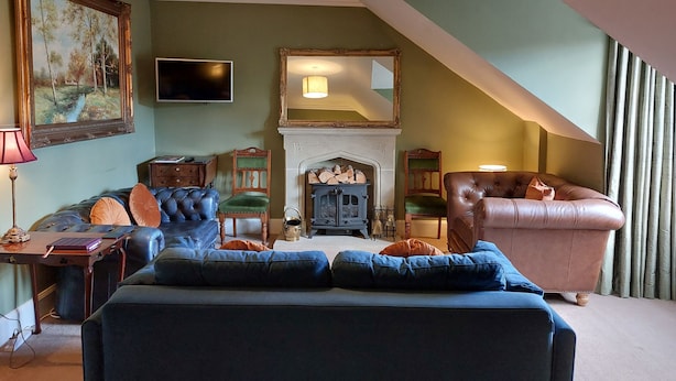 A cozy living room with a fireplace, a large painting, and a comfortable seating area. - Stunning 5BR Royal Mile Penthouse (Edinburgh)