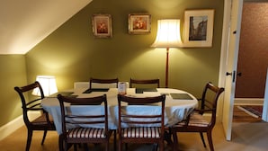 A dining room with a round table, six chairs, and two wall-mounted lamps. - Stunning 5BR Royal Mile Penthouse (Edinburgh)