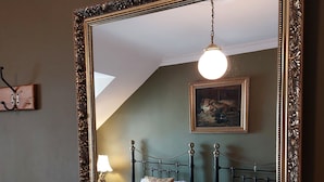 A bedroom with a large ornate mirror, a bed with floral bedding, and a painting on the wall. - Stunning 5BR Royal Mile Penthouse (Edinburgh)