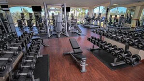 Ein Fitnessstudio mit verschiedenen Gewichtsmaschinen, Spiegeln und Holzboden.