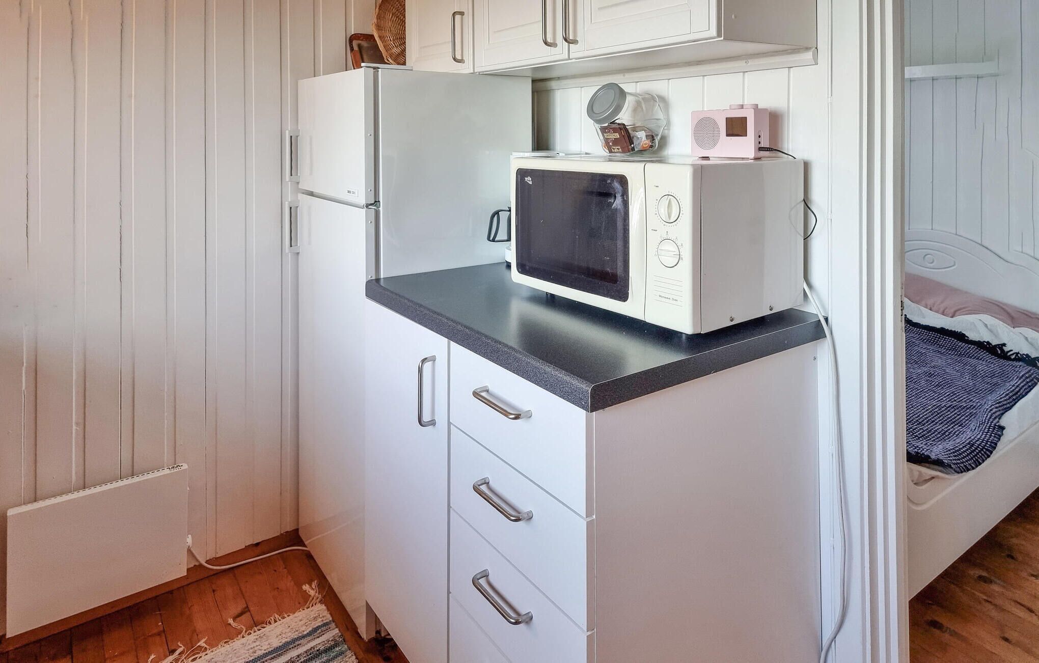 Une petite cuisine équipée comprenant un four à micro-ondes, un petit réfrigérateur et un meuble à tiroirs.