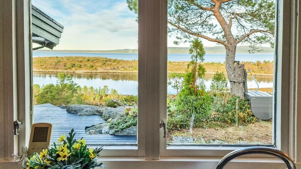 A view from a window overlooking a lake, with a rustic deck and a tree in the foreground. - Cozy home in Kjørsvikbugen with WiFi (Kjørsvikbugen)