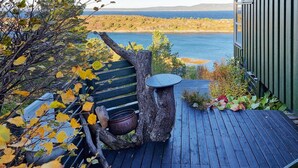 A wooden deck with a rustic table and a hanging pot, overlooking a body of water and a distant landscape. - Cozy home in Kjørsvikbugen with WiFi (Kjørsvikbugen)