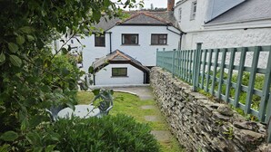 Une maison blanche avec un mur en pierre et une clôture verte.