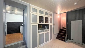 Eine moderne Küche mit weißen Schränken, Holzboden und einer Wendeltreppe aus dunklem Holz.