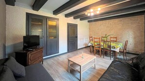 Ein Wohnzimmer mit einer Couch, einem Couchtisch, einem Fernseher und einem Essbereich mit Stühlen und Tisch.