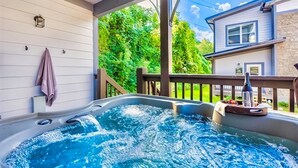 A hot tub with a wooden deck and a stone wall in the background.