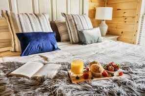 A bed with striped pillows, a book, a glass of orange juice, and a plate with strawberries and muffins. - Sunshine Getaway! Pool,Hot Tub, Playground, Arcade (Pigeon Forge)