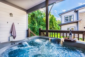 Relax in the hot tub on the deck, surrounded by lush greenery and a serene atmosphere.