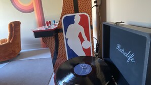 A room with a turntable, a wall with a large NBA logo, and a TV mounted on the wall. - New Lovely Home in Lockhart with a Lounge (Lockhart)