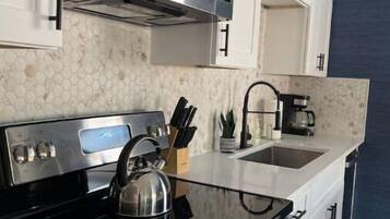 Une cuisine moderne équipée d’appareils électroménagers en acier inoxydable, d’une bouilloire et d’une machine à café.