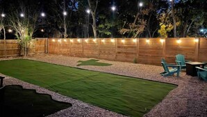A backyard with a wooden fence, string lights, a grassy lawn, and outdoor furniture. - New Lovely Home in Lockhart with a Lounge (Lockhart)