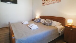 A neatly made bed with folded towels, a wooden headboard, and bedside lamps.