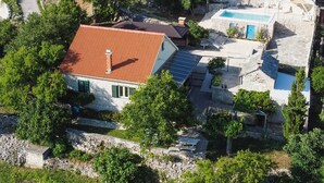 A house with a red roof, solar panels, a swimming pool, and stone walls.