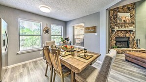 A dining area with a wooden table, chairs, and a kitchen sign on the wall.