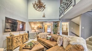 A spacious living room with a large sectional sofa, a wooden console table, and a chandelier.