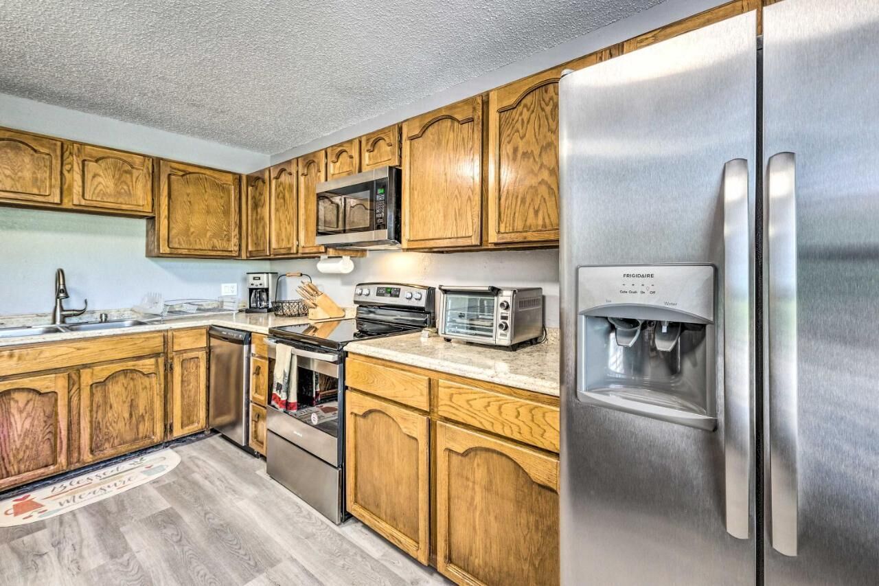 A kitchen with wooden cabinets, stainless steel appliances including a refrigerator, microwave, and toaster, and a built-in oven.