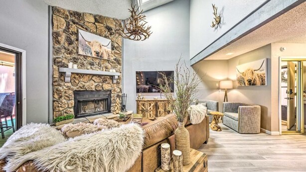 A spacious living area with a stone wall, fireplace, and modern furniture.