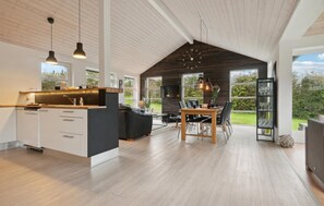 A spacious kitchen with a large island, a dining area with a wooden table, and a view of the outdoors. - Cozy home in Struer with WiFi (Struer)