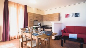 A modern living space with a dining area, kitchen, and a red sofa with a laptop. - "Villa Imelda" spacious, bright apartments, garden or balcony, lake view (Limone Sul Garda)